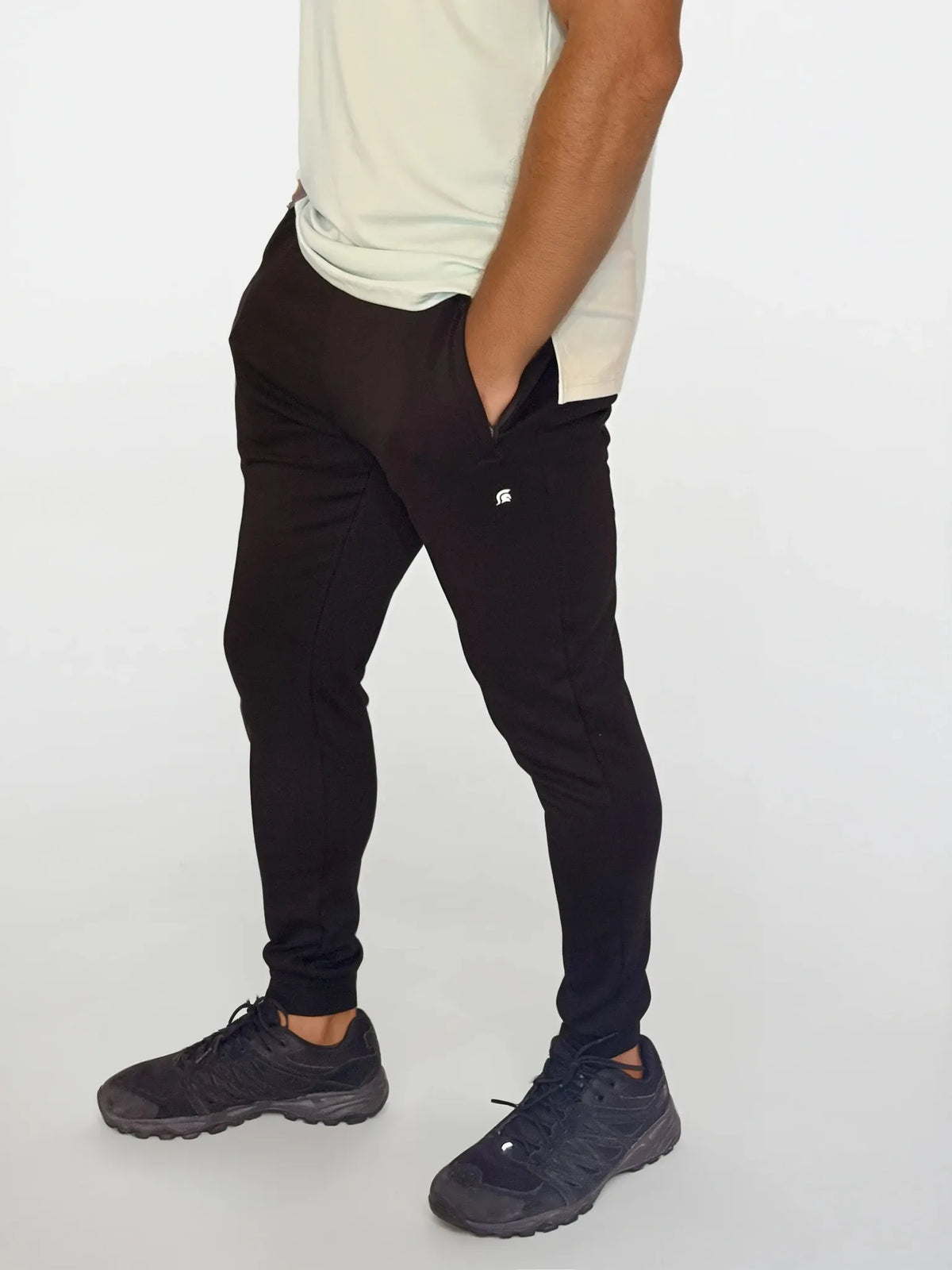 Person wearing black pants and black shoes on a white background