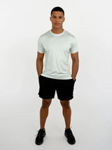 Person wearing a light gray t-shirt and black shorts on a white background