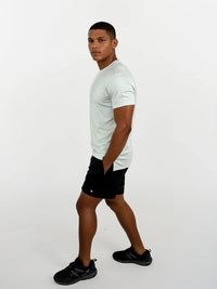 Man wearing a white t-shirt, black shorts, and black shoes on a white background