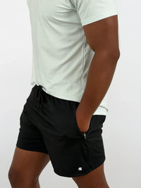 Person wearing black shorts and a white shirt on a plain background