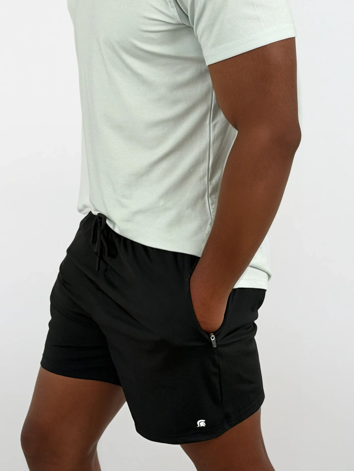 Person wearing black shorts and a white shirt on a plain background